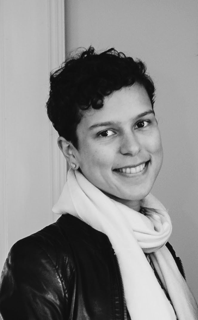 black and white head shot, short hair, wearing a scarf and leather jacket
