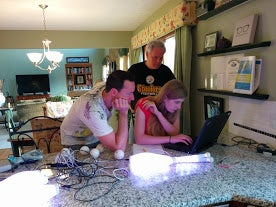 Working on a Raspberry Pi powered juggling pins Lauren, Charles, and her dad around the laptop