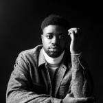 A boy is the dark wearing a black jacket and a white turtleneck